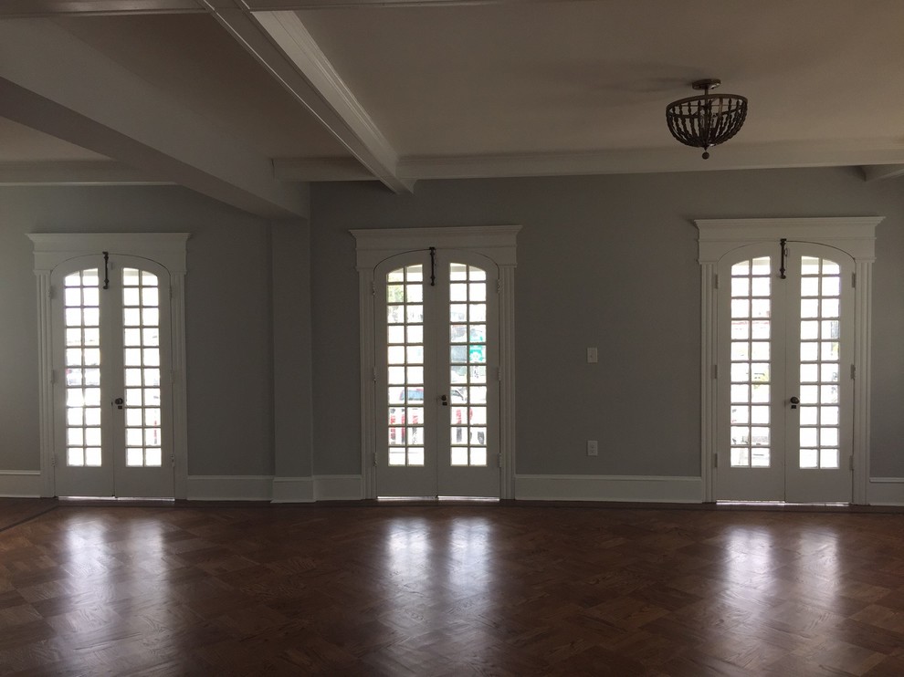 This is an example of a large classic formal open plan living room in Philadelphia with grey walls, medium hardwood flooring, a standard fireplace, a brick fireplace surround and no tv.