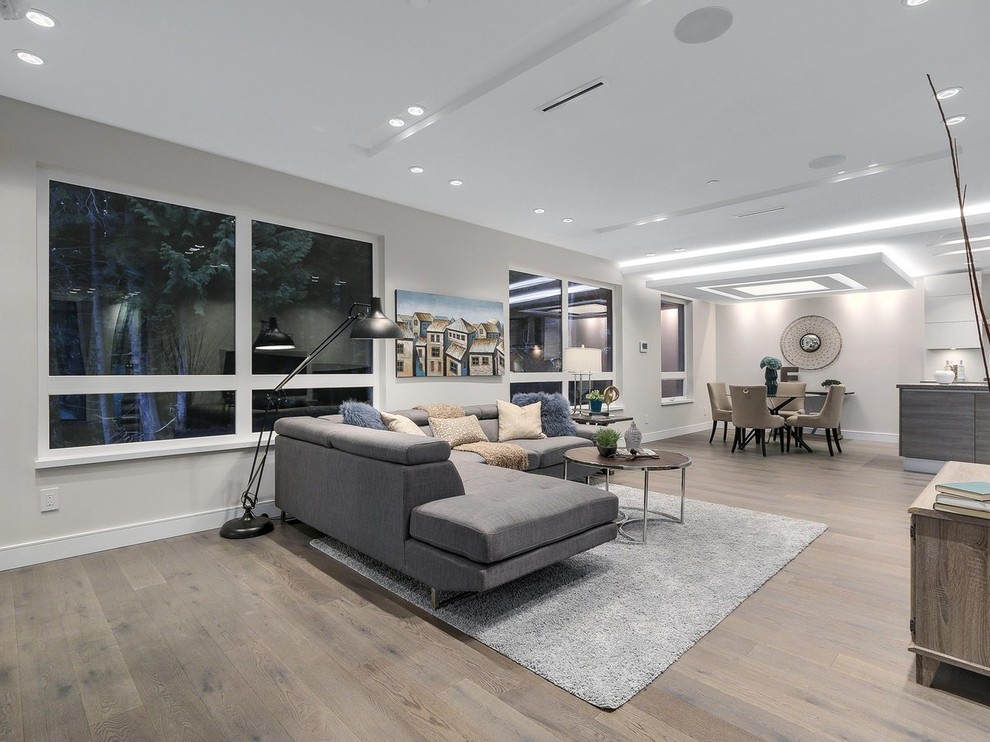 Medium sized contemporary open plan living room in Vancouver with grey walls, light hardwood flooring, a standard fireplace, a stone fireplace surround, a freestanding tv and beige floors.