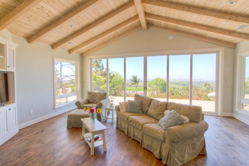 This is an example of an expansive traditional formal open plan living room in Santa Barbara with medium hardwood flooring, a built-in media unit, white walls, a standard fireplace and a tiled fireplace surround.