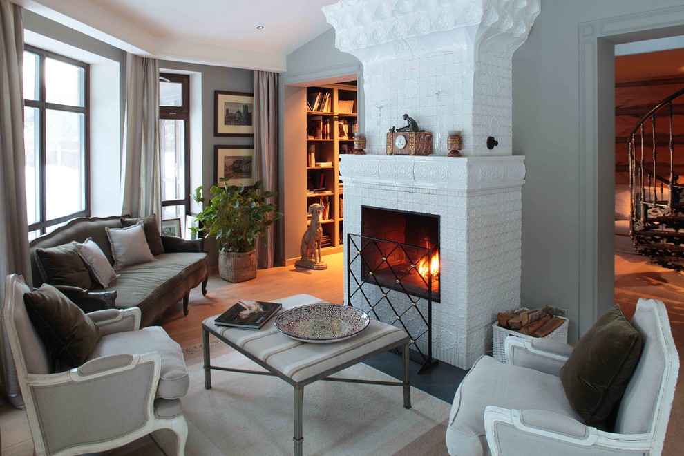 На фото: парадная гостиная комната в классическом стиле с серыми стенами, стандартным камином и паркетным полом среднего тона с