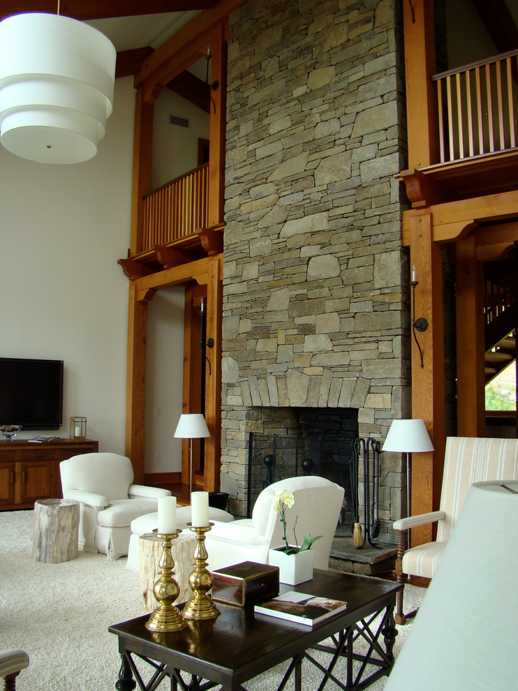 Идея дизайна: большая двухуровневая гостиная комната в стиле кантри с белыми стенами, стандартным камином, фасадом камина из камня, телевизором на стене и темным паркетным полом
