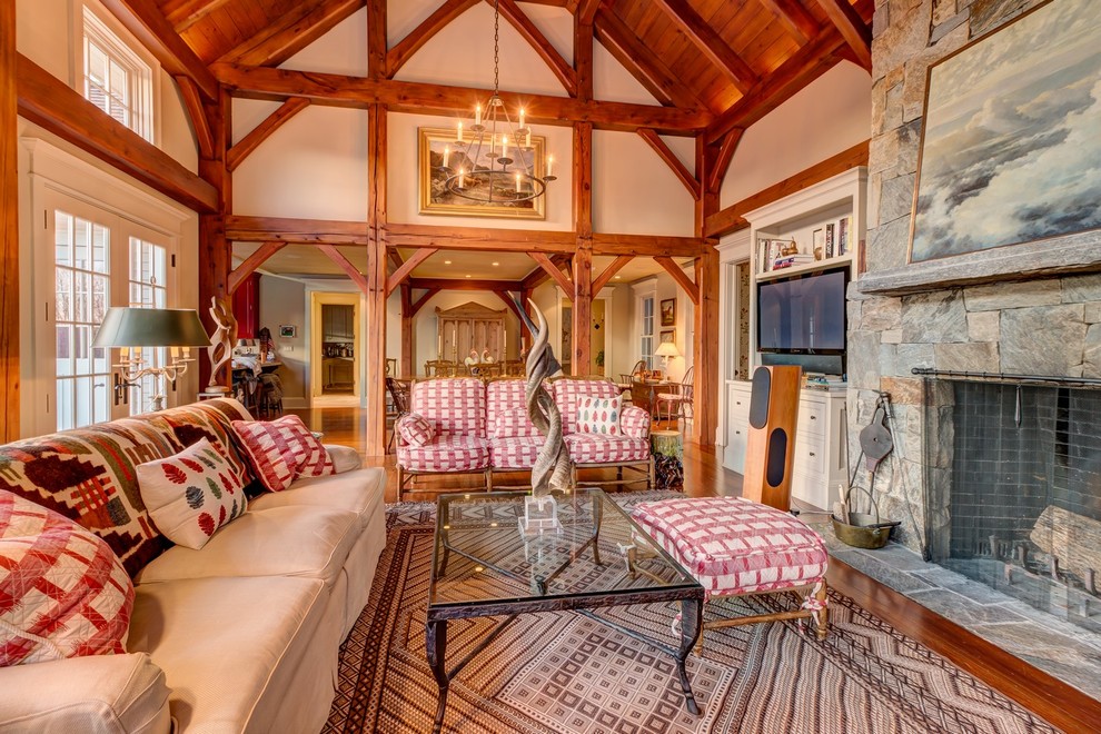 Ejemplo de salón abierto de estilo de casa de campo grande con suelo de madera en tonos medios, todas las chimeneas, marco de chimenea de piedra y pared multimedia