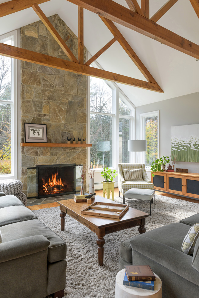 Inspiration pour un salon design avec un mur gris, parquet clair, une cheminée standard et un manteau de cheminée en pierre.