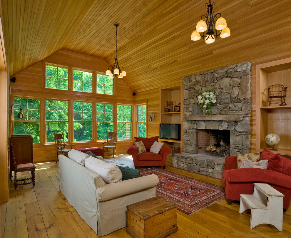 Großes Klassisches Wohnzimmer mit braunem Holzboden, Kamin, Kaminumrandung aus Stein und freistehendem TV in Burlington
