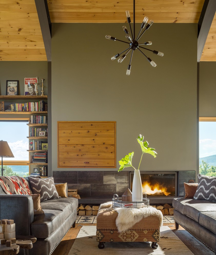 Inspiration pour un grand salon minimaliste ouvert avec un mur gris, un sol en bois brun, une cheminée standard, un manteau de cheminée en plâtre, aucun téléviseur et un sol marron.
