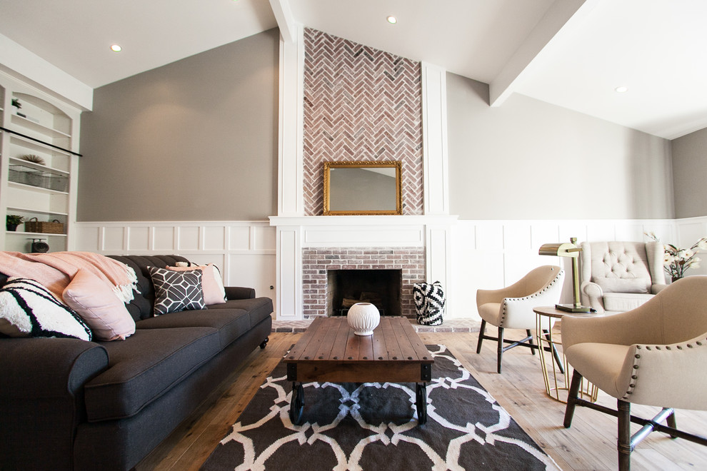 На фото: открытая гостиная комната среднего размера в стиле кантри с серыми стенами, паркетным полом среднего тона, стандартным камином и фасадом камина из кирпича