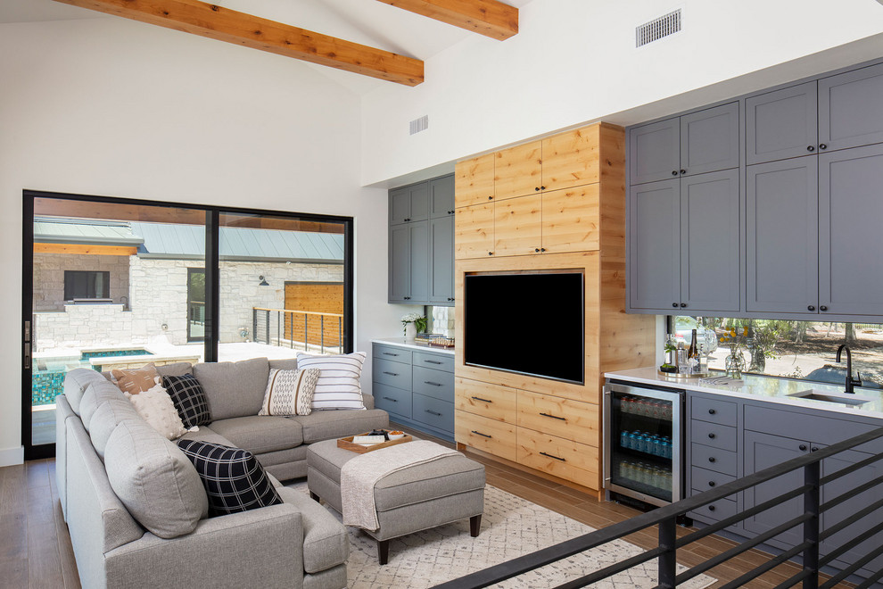 Mittelgroßes Landhaus Wohnzimmer ohne Kamin, im Loft-Stil mit Hausbar, weißer Wandfarbe, braunem Holzboden und Multimediawand in Austin