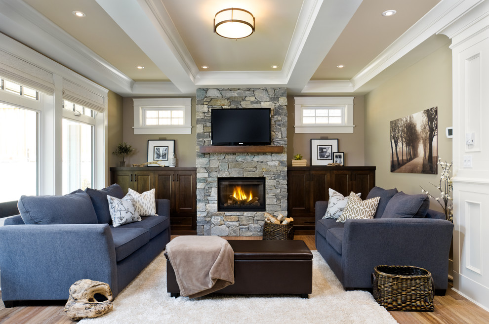 Living room - traditional enclosed medium tone wood floor living room idea in Vancouver with beige walls, a standard fireplace, a stone fireplace and a wall-mounted tv