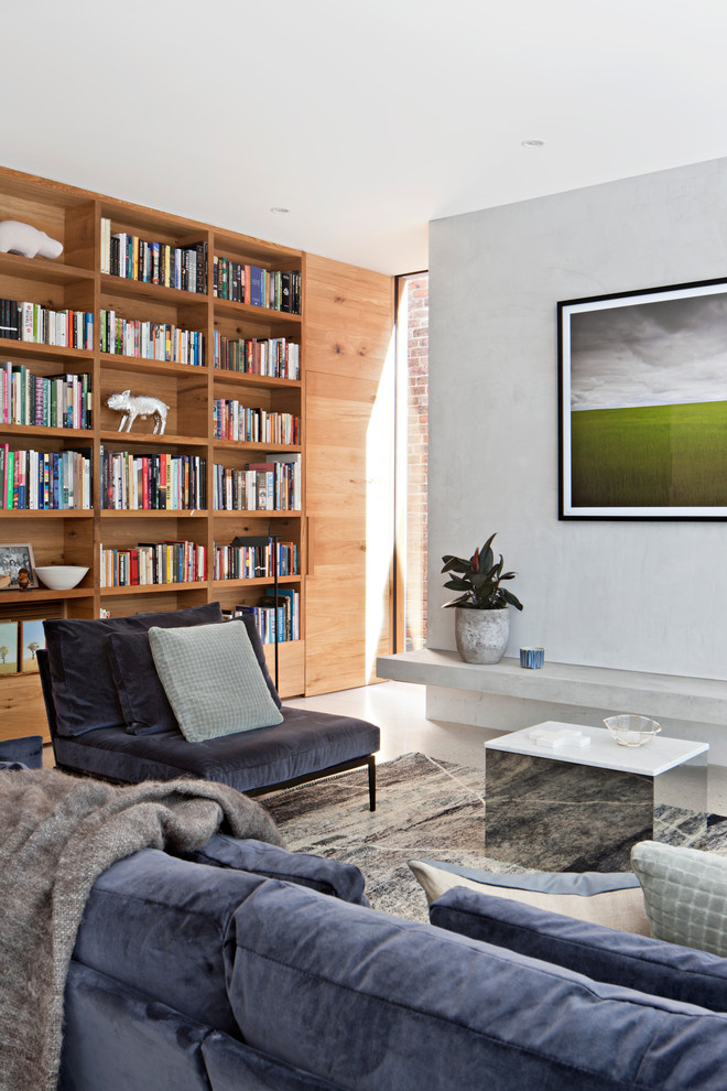 Стильный дизайн: изолированная гостиная комната среднего размера в современном стиле с с книжными шкафами и полками, бетонным полом, белыми стенами, белым полом и синим диваном - последний тренд