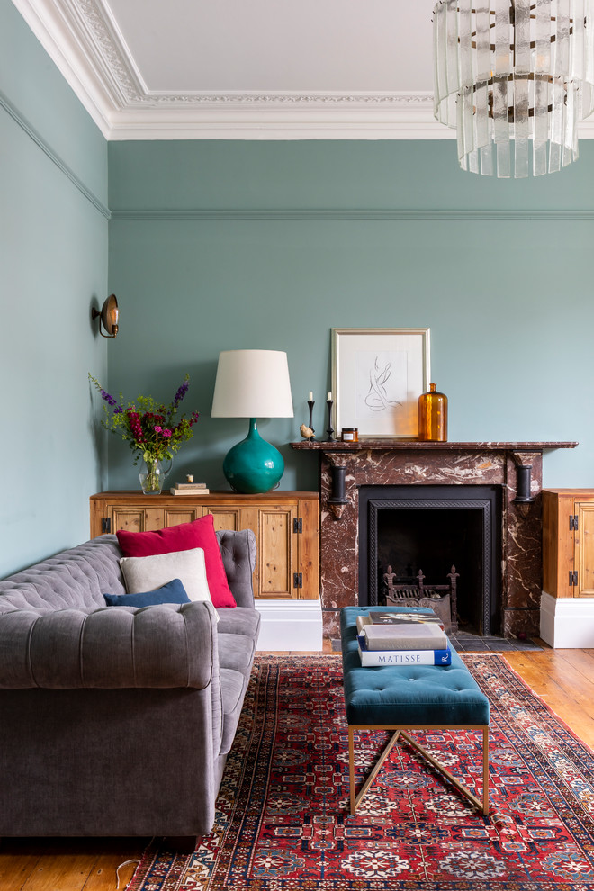 Inspiration för ett vintage vardagsrum, med en spiselkrans i sten, blå väggar, mellanmörkt trägolv, en standard öppen spis och brunt golv