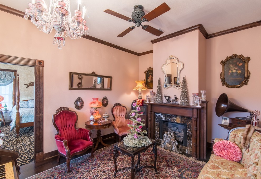 Стильный дизайн: большая парадная, изолированная гостиная комната в викторианском стиле с розовыми стенами, темным паркетным полом, стандартным камином, фасадом камина из камня и коричневым полом без телевизора - последний тренд