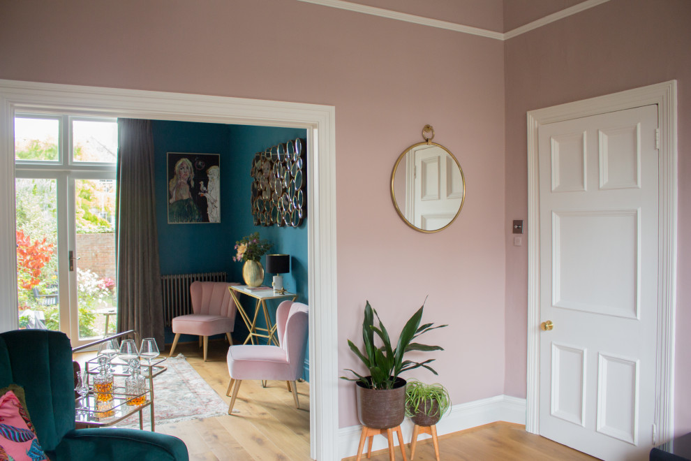 Стильный дизайн: изолированная гостиная комната среднего размера в стиле фьюжн с домашним баром, розовыми стенами, полом из ламината, стандартным камином, фасадом камина из камня и телевизором на стене - последний тренд
