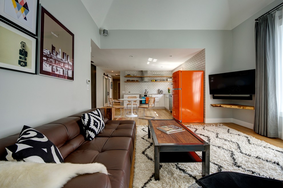 Bild på ett mellanstort funkis allrum med öppen planlösning, med grå väggar, ljust trägolv och en väggmonterad TV