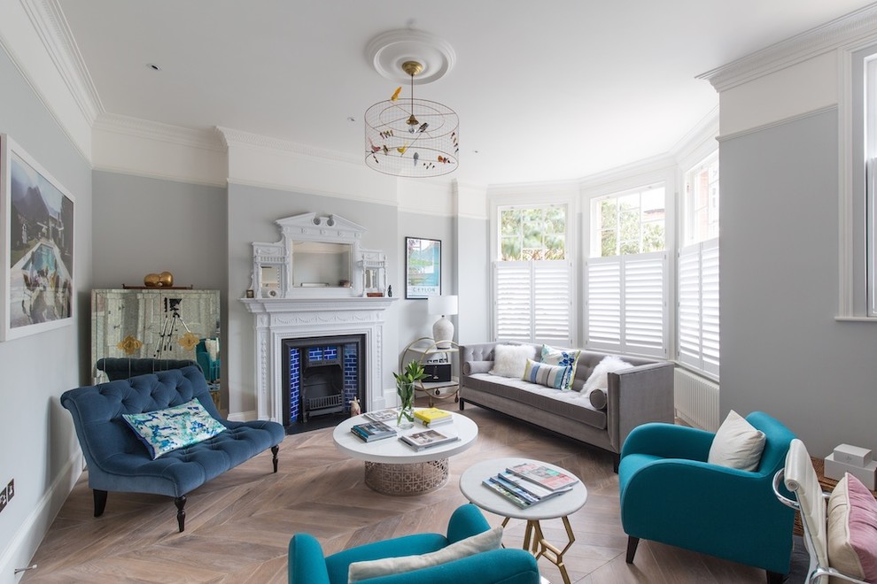 Photo of a classic grey and teal living room in London with grey walls, light hardwood flooring, a standard fireplace and no tv.