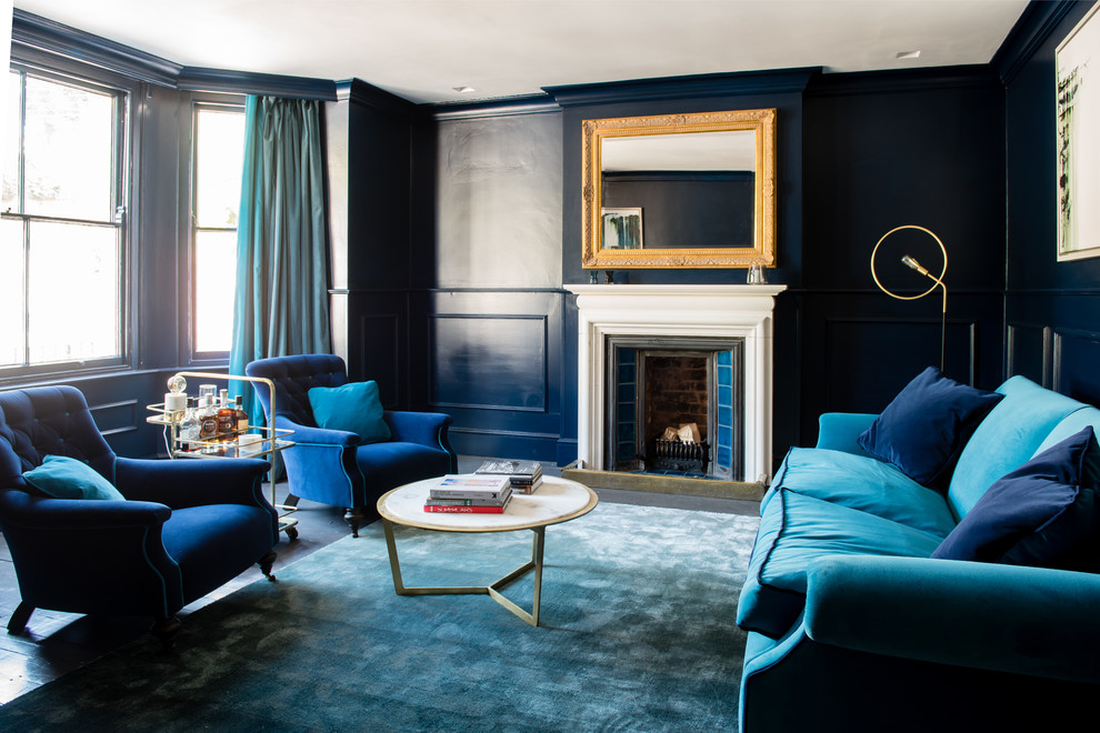 Idee per un soggiorno vittoriano con pareti blu, pavimento in legno verniciato, camino classico e TV nascosta