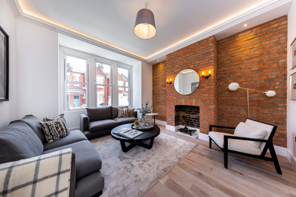 Example of a transitional formal and enclosed medium tone wood floor, brown floor and brick wall living room design in Other with white walls, a standard fireplace, a brick fireplace and no tv
