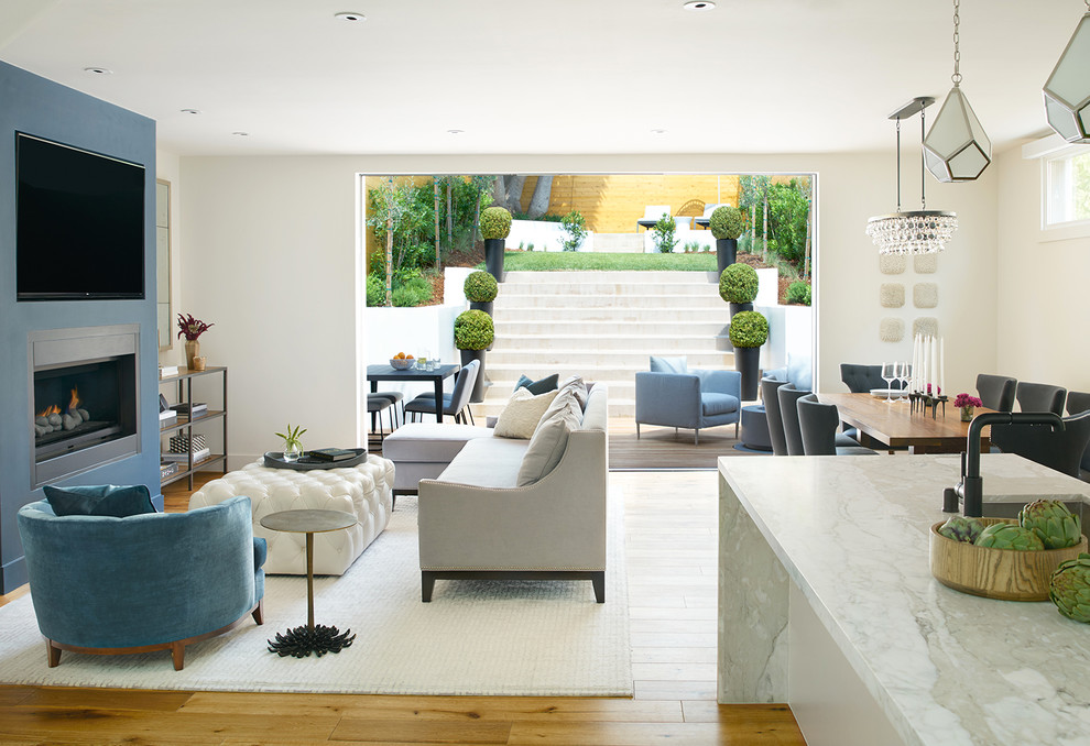 Inspiration for a mid-sized transitional open concept medium tone wood floor living room remodel in San Francisco with a standard fireplace, blue walls and a wall-mounted tv
