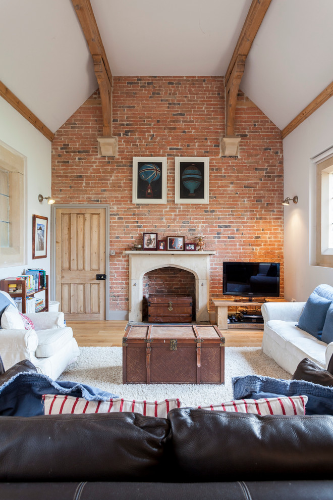 Modelo de salón cerrado de estilo de casa de campo con paredes blancas, todas las chimeneas, televisor independiente y suelo de madera clara