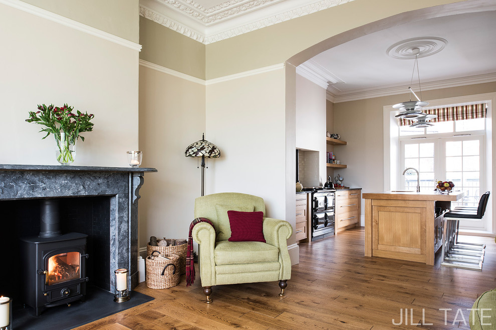 Ejemplo de salón para visitas abierto tradicional de tamaño medio con paredes beige, suelo de madera en tonos medios, estufa de leña y marco de chimenea de piedra