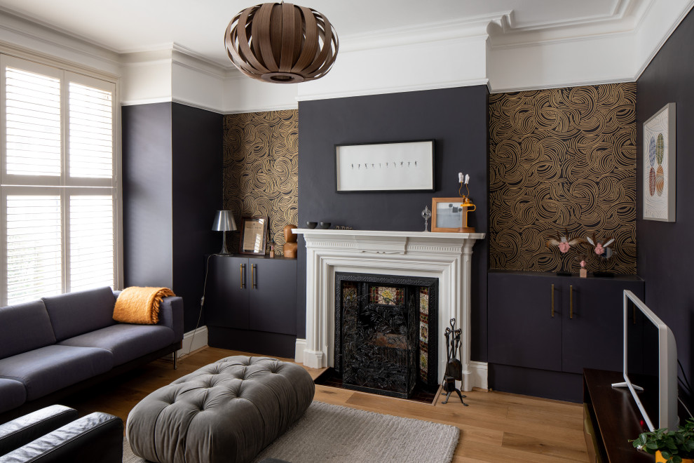 Photo of a medium sized contemporary formal enclosed living room in London with black walls, medium hardwood flooring, a standard fireplace, a tiled fireplace surround, a freestanding tv and brown floors.
