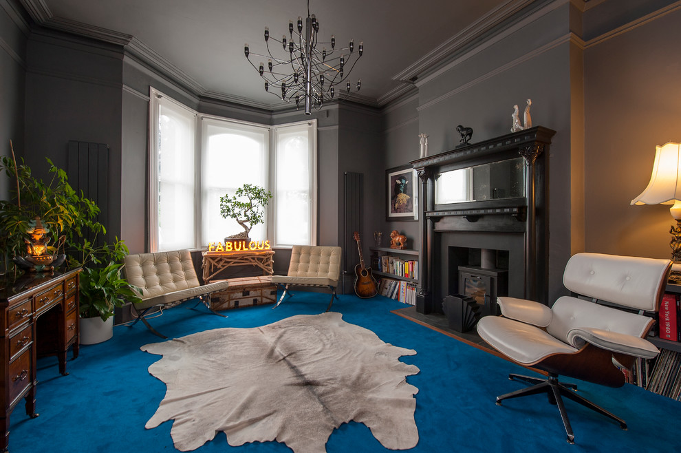 На фото: гостиная комната в стиле фьюжн с серыми стенами, ковровым покрытием и печью-буржуйкой с