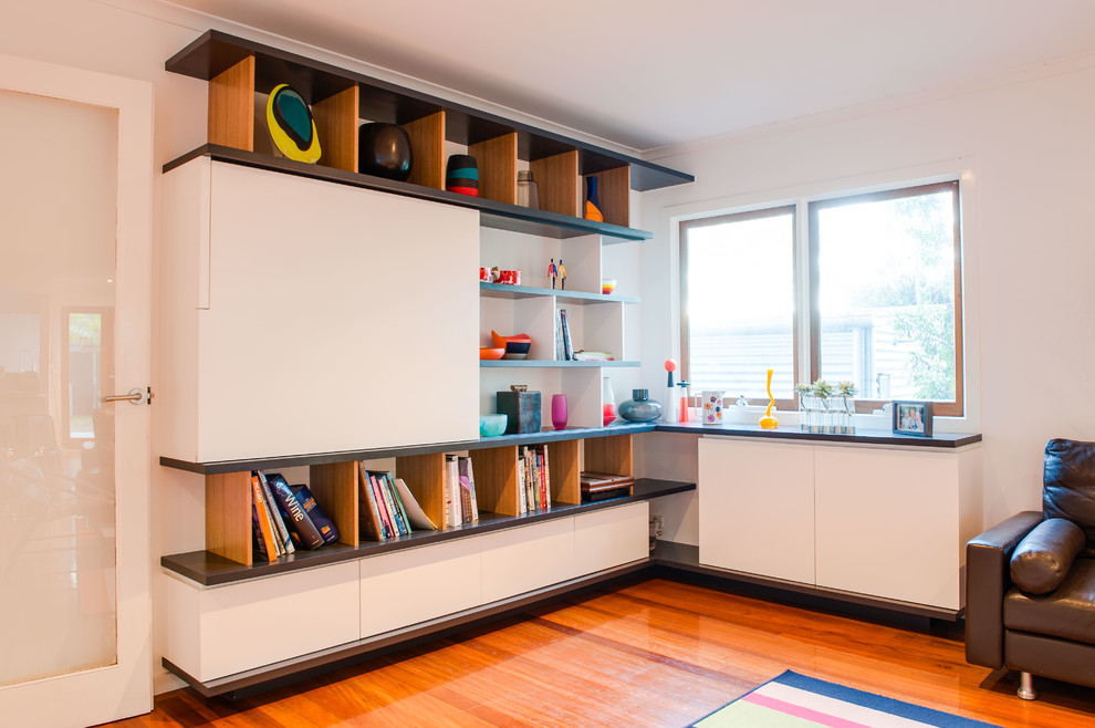 Idee per un soggiorno minimal di medie dimensioni e aperto con libreria, pareti bianche, parquet chiaro e parete attrezzata