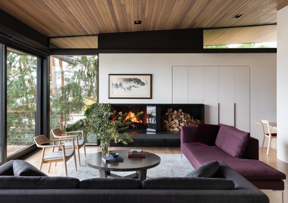 Diseño de salón abierto contemporáneo con paredes blancas, suelo de madera en tonos medios, chimenea lineal, marco de chimenea de metal y madera