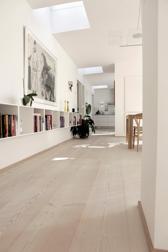 Inspiration för ett stort minimalistiskt allrum med öppen planlösning, med vita väggar och ljust trägolv