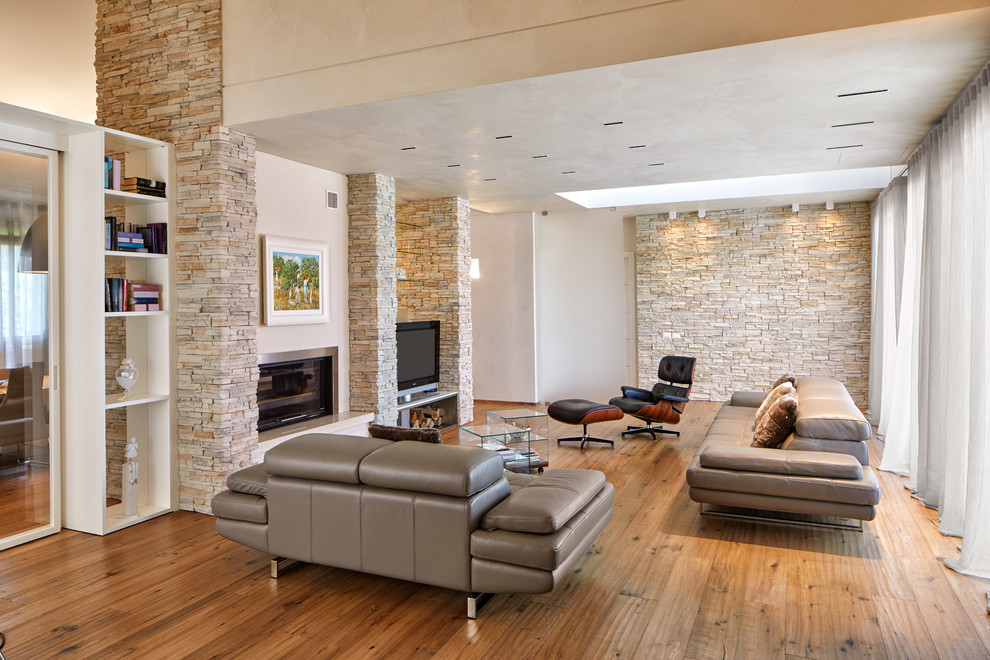 Idee per un soggiorno minimal con pareti beige, pavimento in legno massello medio, camino classico, TV autoportante e pavimento marrone