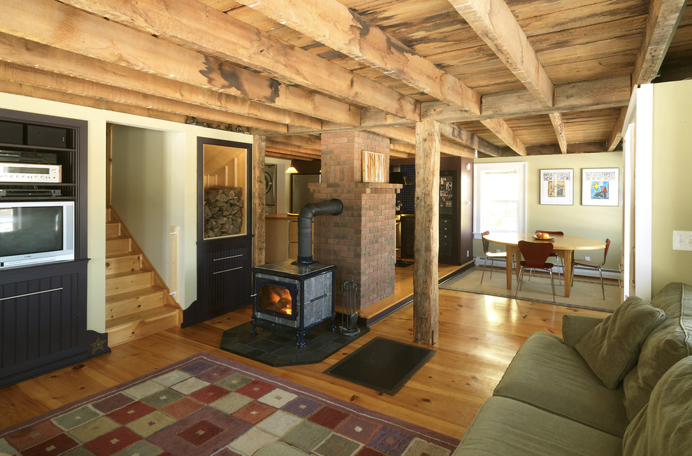 Inspiration for a mid-sized farmhouse open concept medium tone wood floor living room remodel in Burlington with beige walls, a wood stove and a media wall