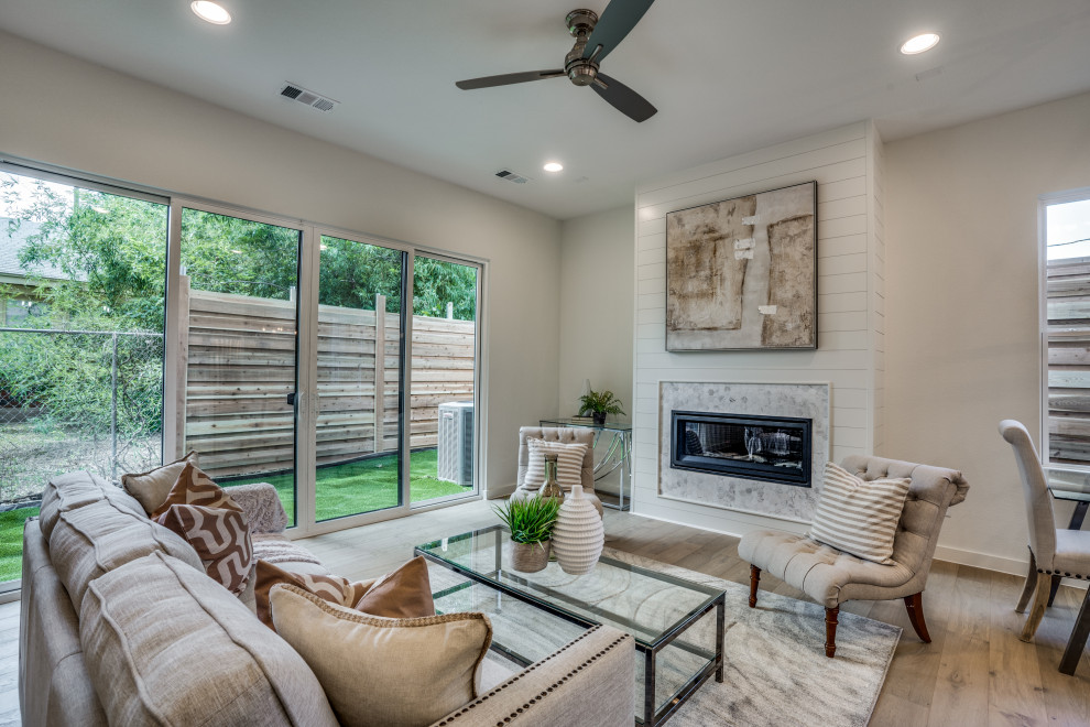 Landhaus Wohnzimmer mit weißer Wandfarbe, braunem Holzboden, Kamin, Kaminumrandung aus Holzdielen und braunem Boden in Dallas