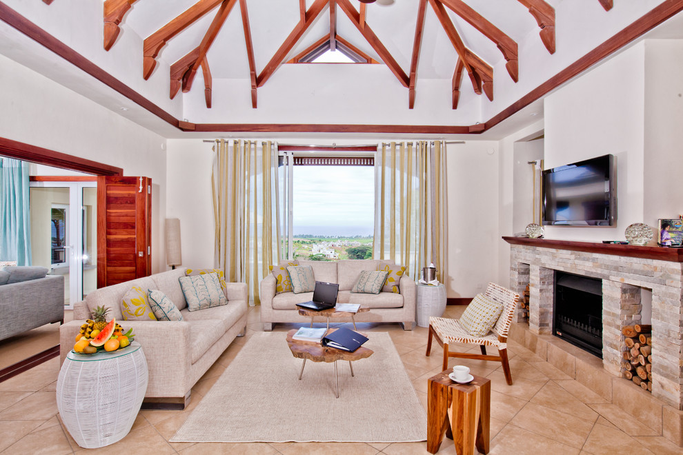 Esempio di un soggiorno tropicale con sala formale, pareti bianche, camino classico, cornice del camino in pietra e TV a parete