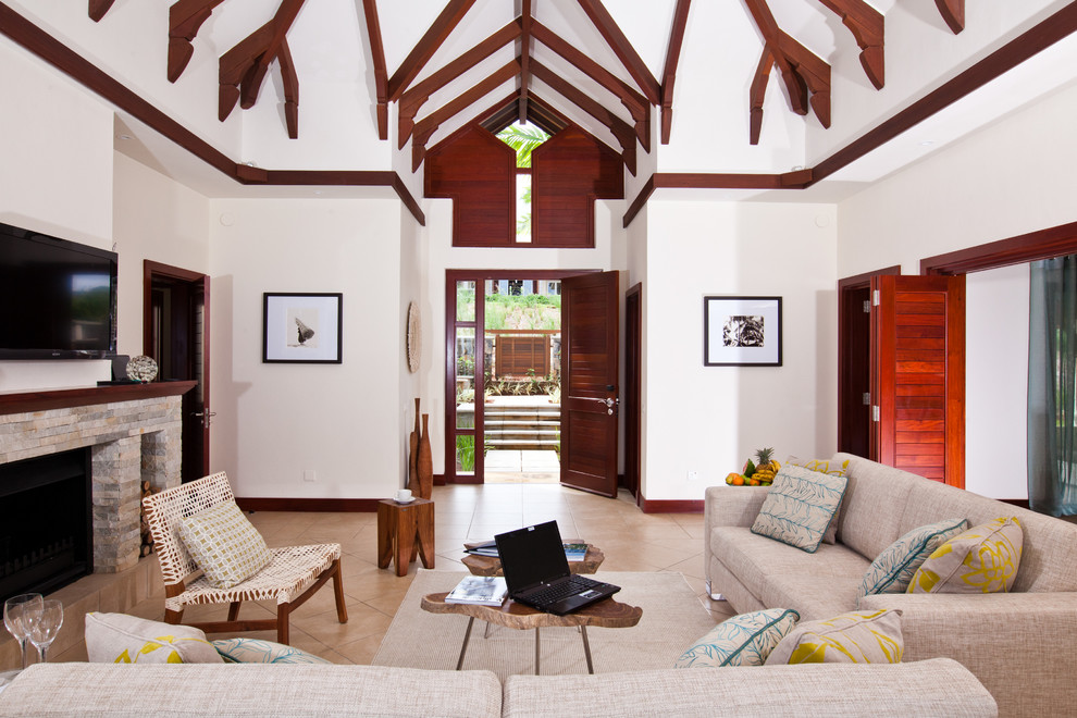 Источник вдохновения для домашнего уюта: гостиная комната в морском стиле с белыми стенами, полом из травертина, телевизором на стене, стандартным камином и фасадом камина из камня