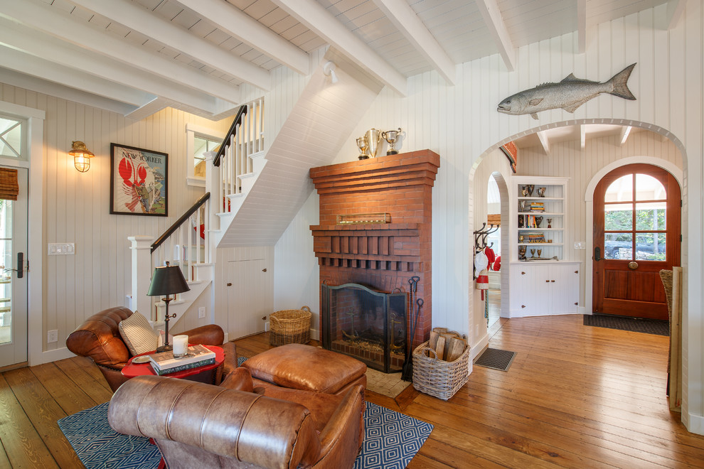 Offenes Maritimes Wohnzimmer mit weißer Wandfarbe, braunem Holzboden, Kamin und Kaminumrandung aus Backstein in Portland Maine