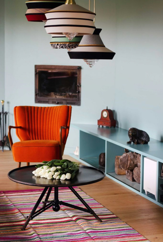 Idée de décoration pour un grand salon vintage ouvert avec un mur vert, un sol en bois brun, une cheminée d'angle, un manteau de cheminée en plâtre, un téléviseur fixé au mur, un sol marron et une salle de réception.