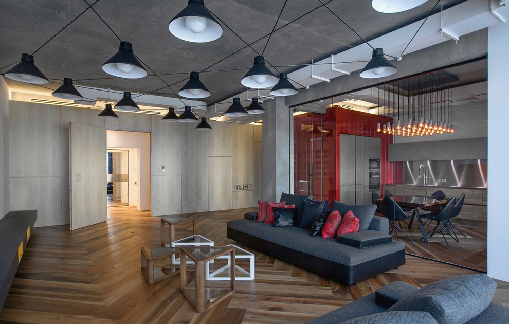 Cette image montre un grand salon urbain ouvert avec un mur gris, un sol en bois brun et aucun téléviseur.