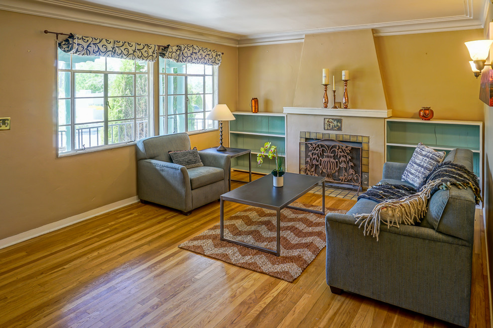 Bild på ett litet amerikanskt separat vardagsrum, med ett finrum, beige väggar, ljust trägolv, en standard öppen spis och en spiselkrans i gips