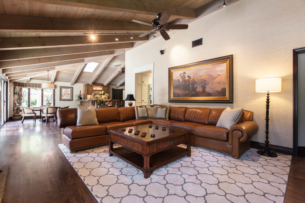 Großes, Offenes Stilmix Wohnzimmer mit beiger Wandfarbe, braunem Holzboden, Kamin und Kaminumrandung aus Stein in San Diego