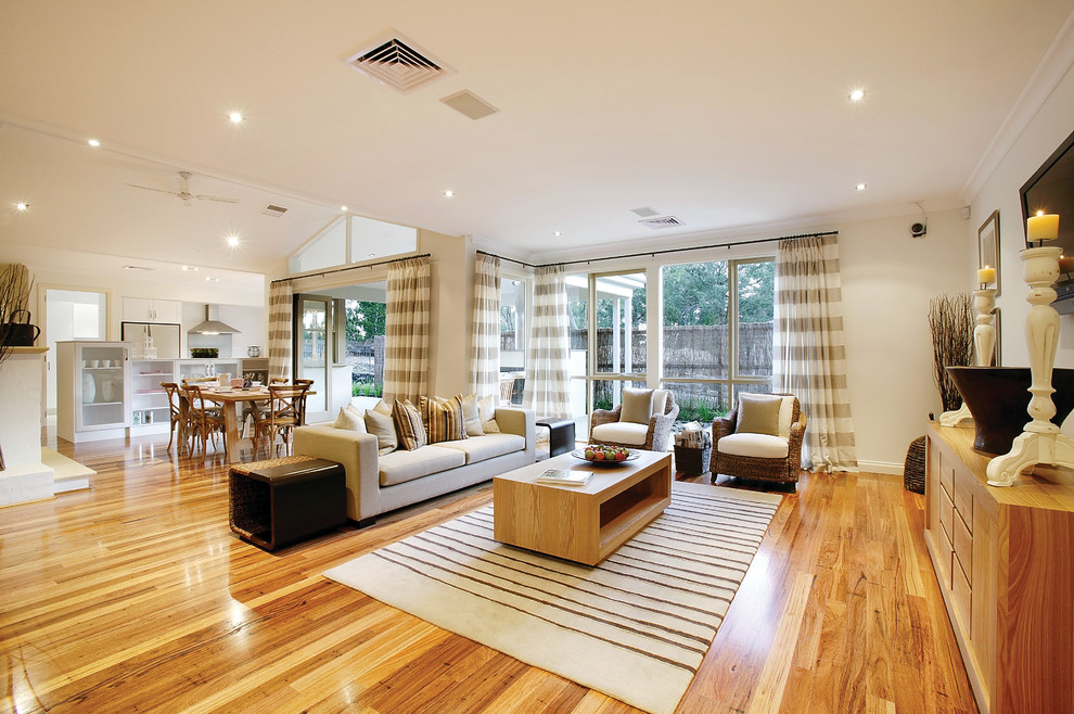Imagen de salón abierto clásico renovado con paredes blancas, suelo de madera en tonos medios, televisor colgado en la pared y suelo marrón