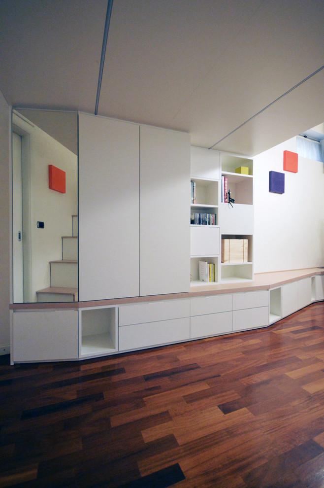 Idee per un piccolo soggiorno minimal aperto con libreria, pareti bianche, pavimento in legno verniciato e pavimento marrone