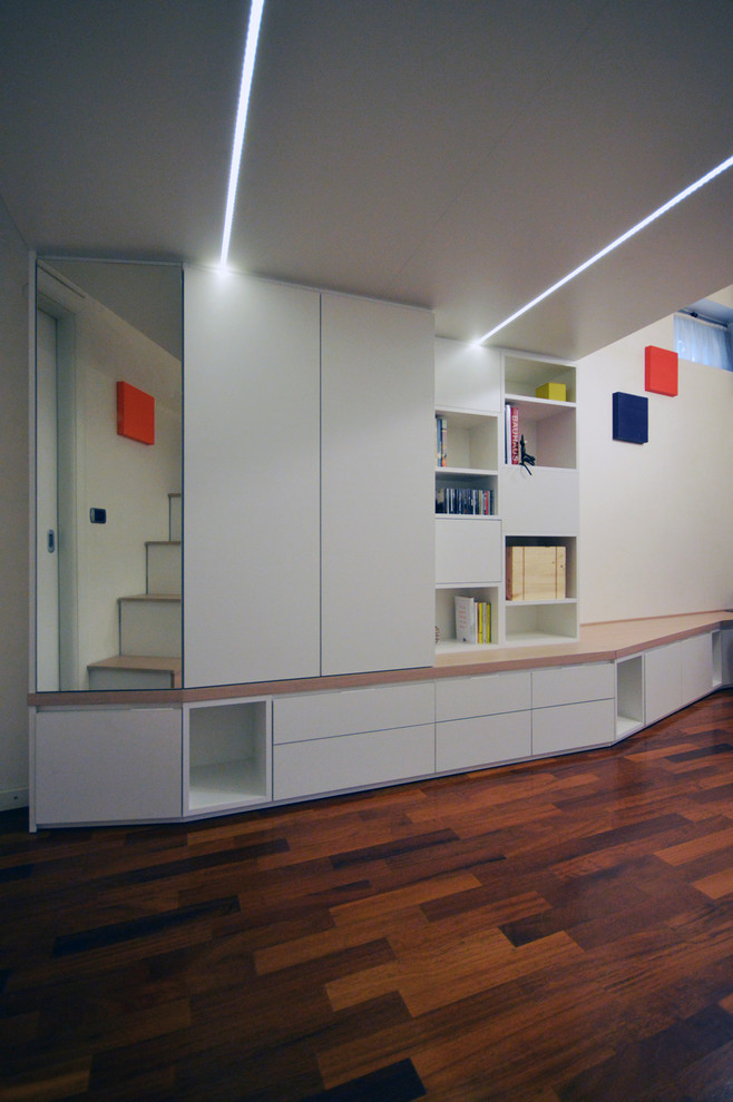 Cette photo montre un petit salon tendance ouvert avec une bibliothèque ou un coin lecture, un mur blanc, parquet peint et un sol marron.