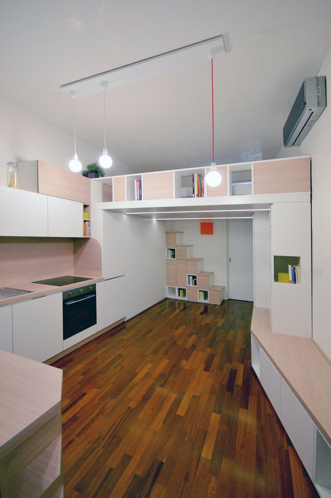 Стильный дизайн: маленькая открытая гостиная комната в современном стиле с с книжными шкафами и полками, белыми стенами, деревянным полом и коричневым полом для на участке и в саду - последний тренд