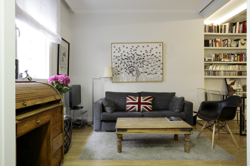 Esempio di un piccolo soggiorno design con libreria e pavimento in legno massello medio