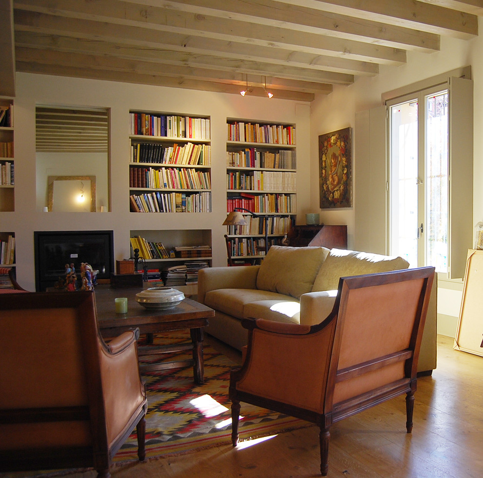На фото: изолированная гостиная комната среднего размера в стиле рустика с с книжными шкафами и полками, бежевыми стенами, паркетным полом среднего тона и стандартным камином с