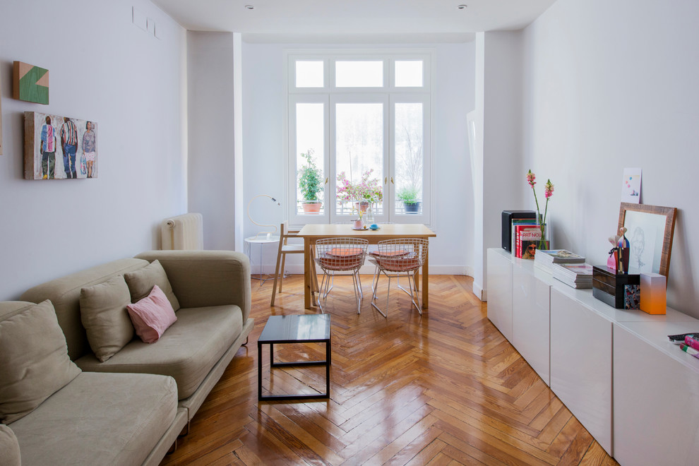 Repräsentatives, Offenes, Mittelgroßes, Fernseherloses Modernes Wohnzimmer ohne Kamin mit weißer Wandfarbe und braunem Holzboden in Madrid