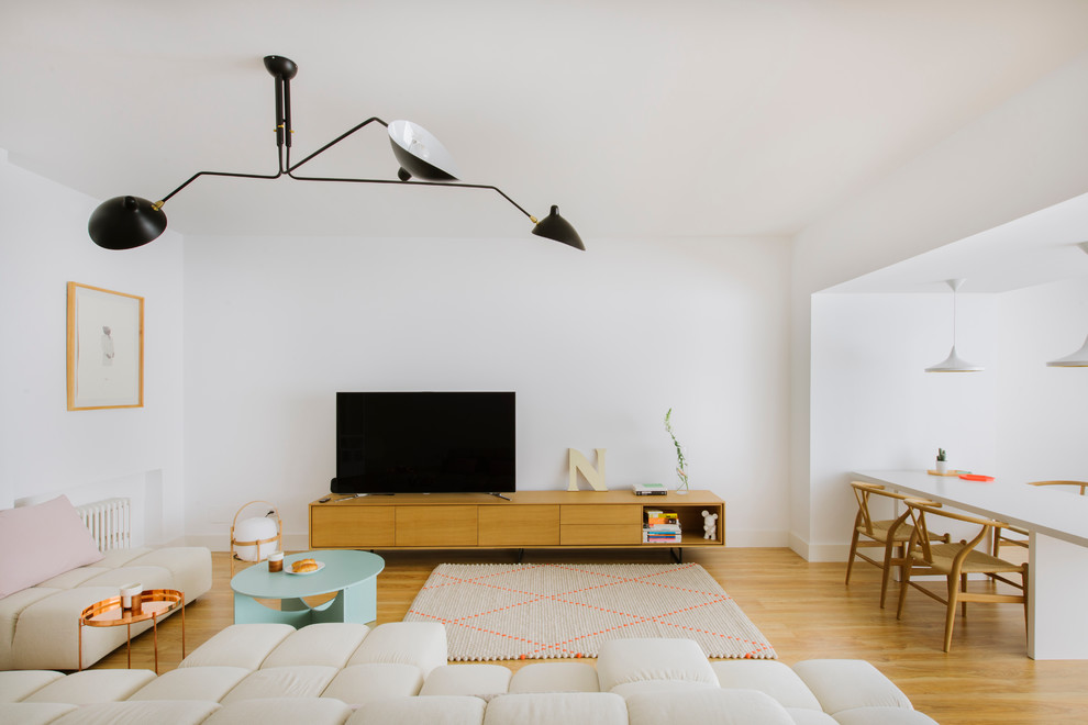 Offenes, Mittelgroßes, Repräsentatives Modernes Wohnzimmer ohne Kamin mit braunem Holzboden, freistehendem TV und weißer Wandfarbe in Madrid