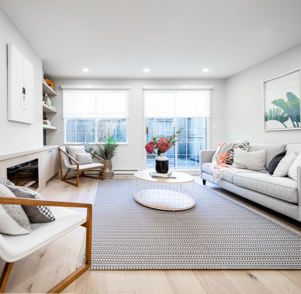 Kleines, Offenes, Fernseherloses Modernes Wohnzimmer mit grauer Wandfarbe, hellem Holzboden, Kaminumrandung aus Holz und Kamin in Vancouver
