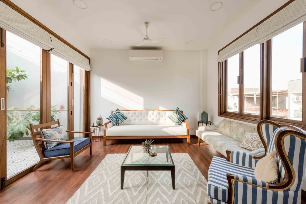 Mittelgroßes, Abgetrenntes Asiatisches Wohnzimmer mit weißer Wandfarbe, braunem Holzboden und braunem Boden in Delhi