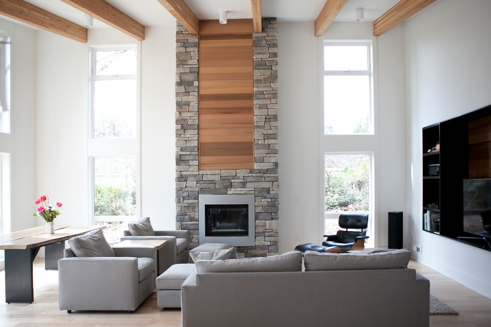 Inspiration pour un salon design ouvert avec un mur blanc, un sol en bois brun, une cheminée standard, un manteau de cheminée en pierre et un téléviseur encastré.