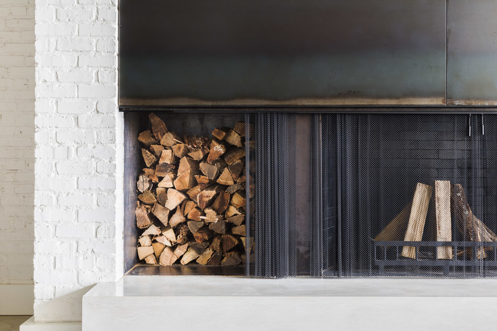 他の地域にあるラグジュアリーな中くらいなインダストリアルスタイルのおしゃれなLDK (標準型暖炉、白い壁、トラバーチンの床、レンガの暖炉まわり、ベージュの床) の写真